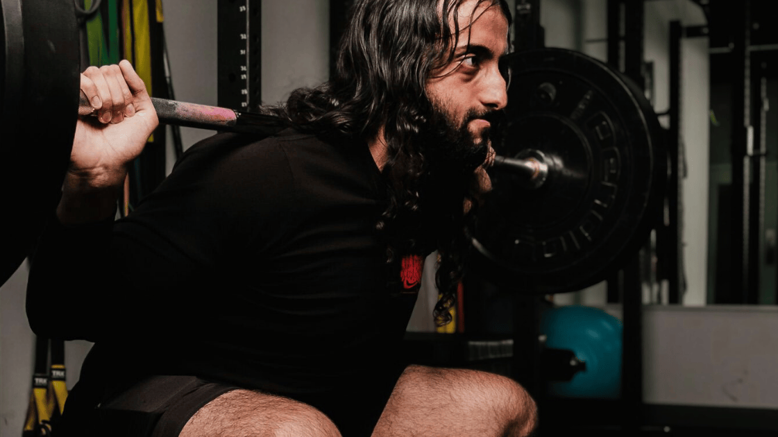 man doet squat in sport shirt